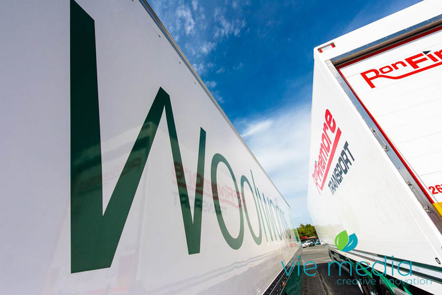 Trucking and logistics image showing two semi trailers in the yard of transport companu, Ron Finemore Transport, with the Woolworths logo beside that of the RFT logo